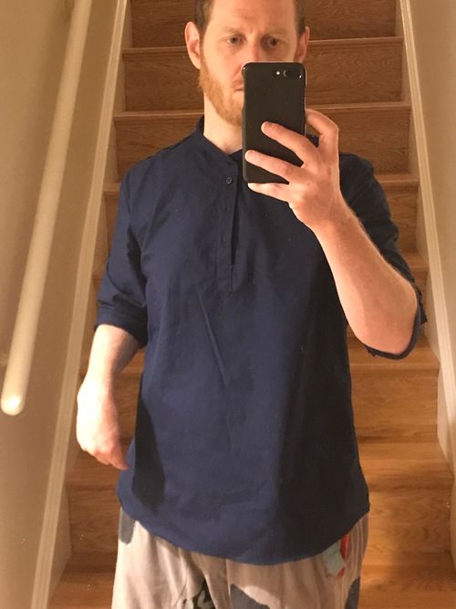 Picture of Raphael wearing a dark blue shirt. The shirt has a low collar (sometimes called a Nehru collar) with a cutout running partway down the front of the shirt, which is a pull-over and does not have a full front opening. It has long sleeves which are rolled up to the elbow.