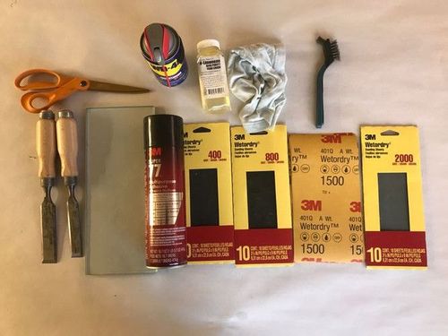 Tools and materials for sharpening: two chisels to sharpen, pair of scissors to cut sandpaper, half-inch piece of float glass, about 4" x 12", Super 77 spray adhesive, D-limonene (solvent, yellow in clear bottle), rag from soft t-shirt, steel wire brush, WD-40, wet-or-dry sandpaper in grits 400, 800, 1500, 2000.