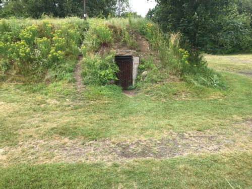A grassy earthwork with a barred door leading into it: WWII fortifications.